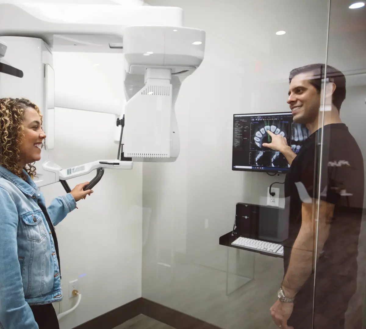 Dr. Kottar showing a patient her 3D scan beside the cone-beam CT scanner