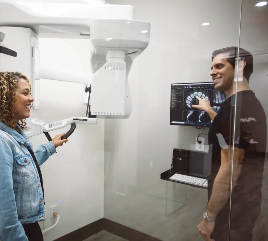 Dr. Kottar showing a patient her 3D scan beside the cone-beam CT scanner