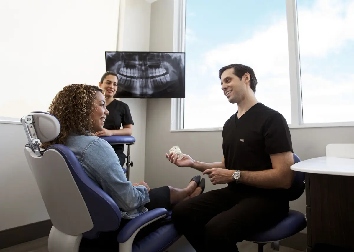 Dr. Kottar showing a patient a model of the teeth, with her X-ray on the screen